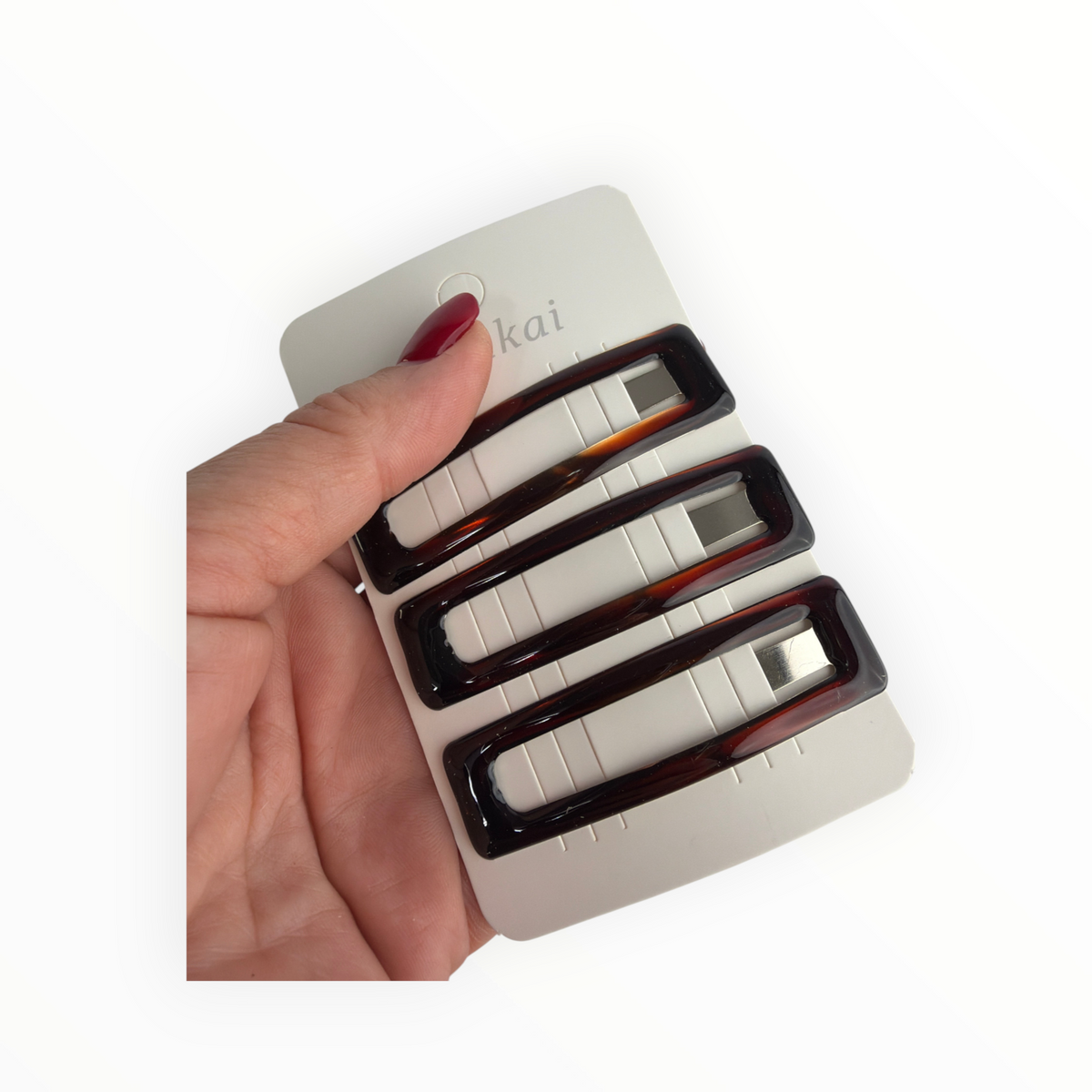 CE Collection rectangular tortoise shell hair clips on a display card held in a hand