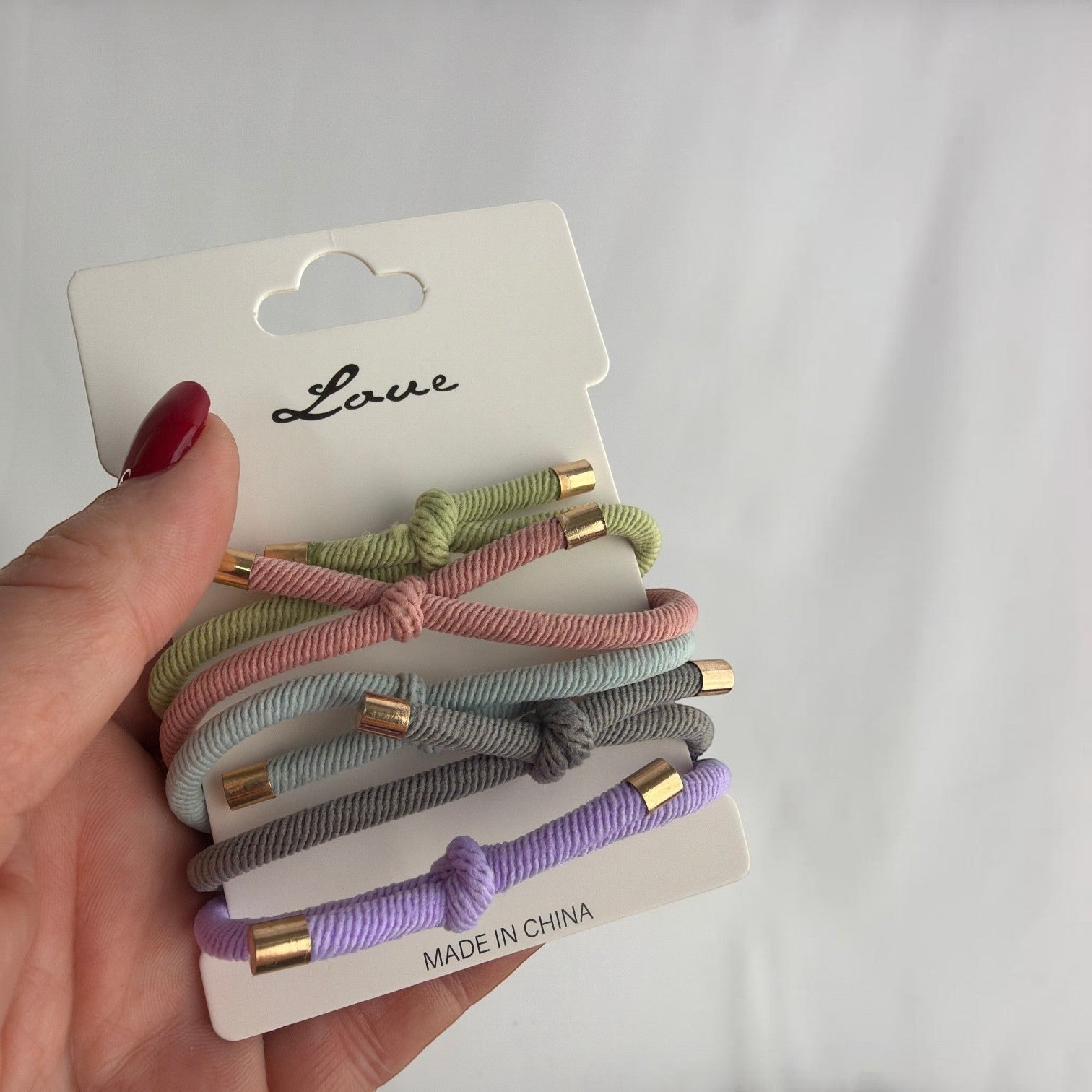 CE Collection pastel hair elastics in green, pink, blue, grey, and purple with gold accents, sold in a pack of 5.